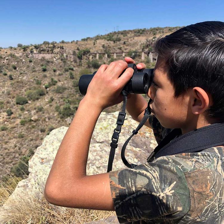 Young Mexican boy surveying the world for the first through binoculars, Photo by Rodrigo López